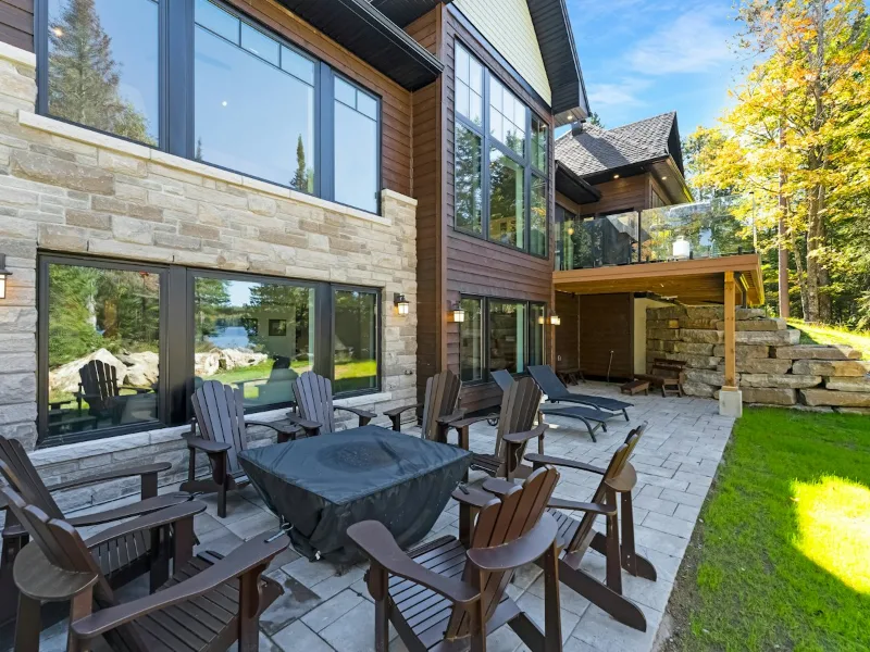 Stone patio with chairs and a fire pit beside a house
